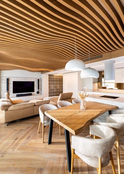 Living and dining space under the Airwood wave ceiling, with a live-edge table and marble kitchen island