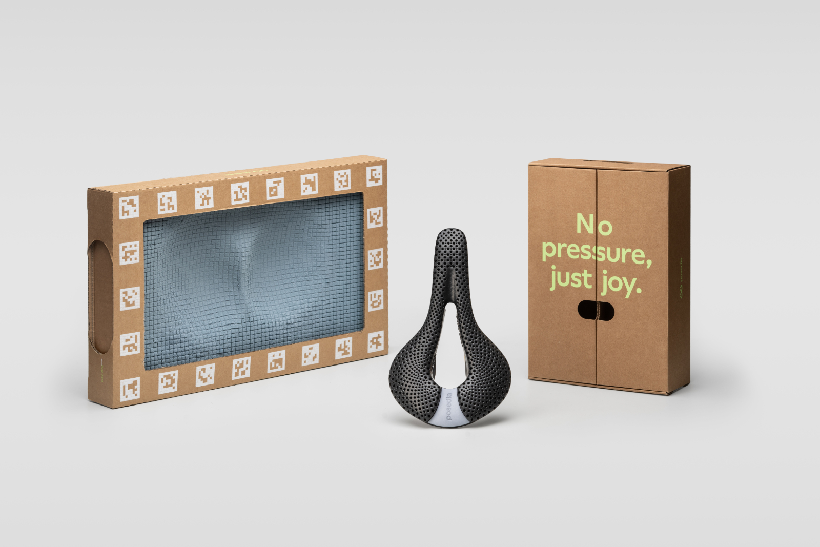 Posedla Joyseat packaging set: a window box showing the sit-bone imprint foam, a saddle standing upright, and a kraft box reading No pressure, just joy